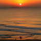 A group of people on the beach as the sun sets.